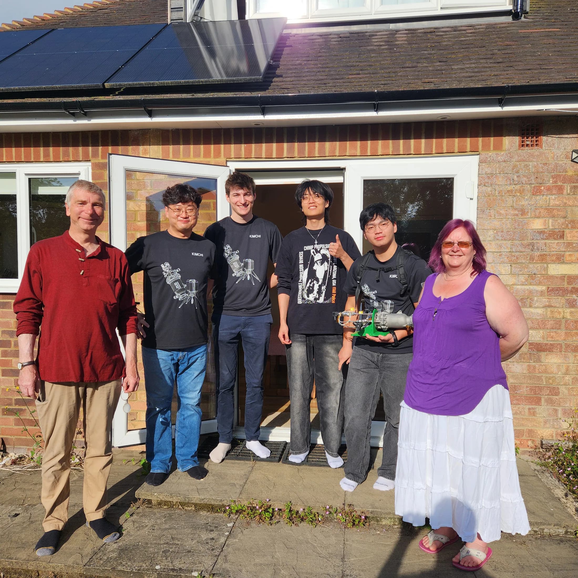 Six team members standing together outside a brick building before test-day activities.