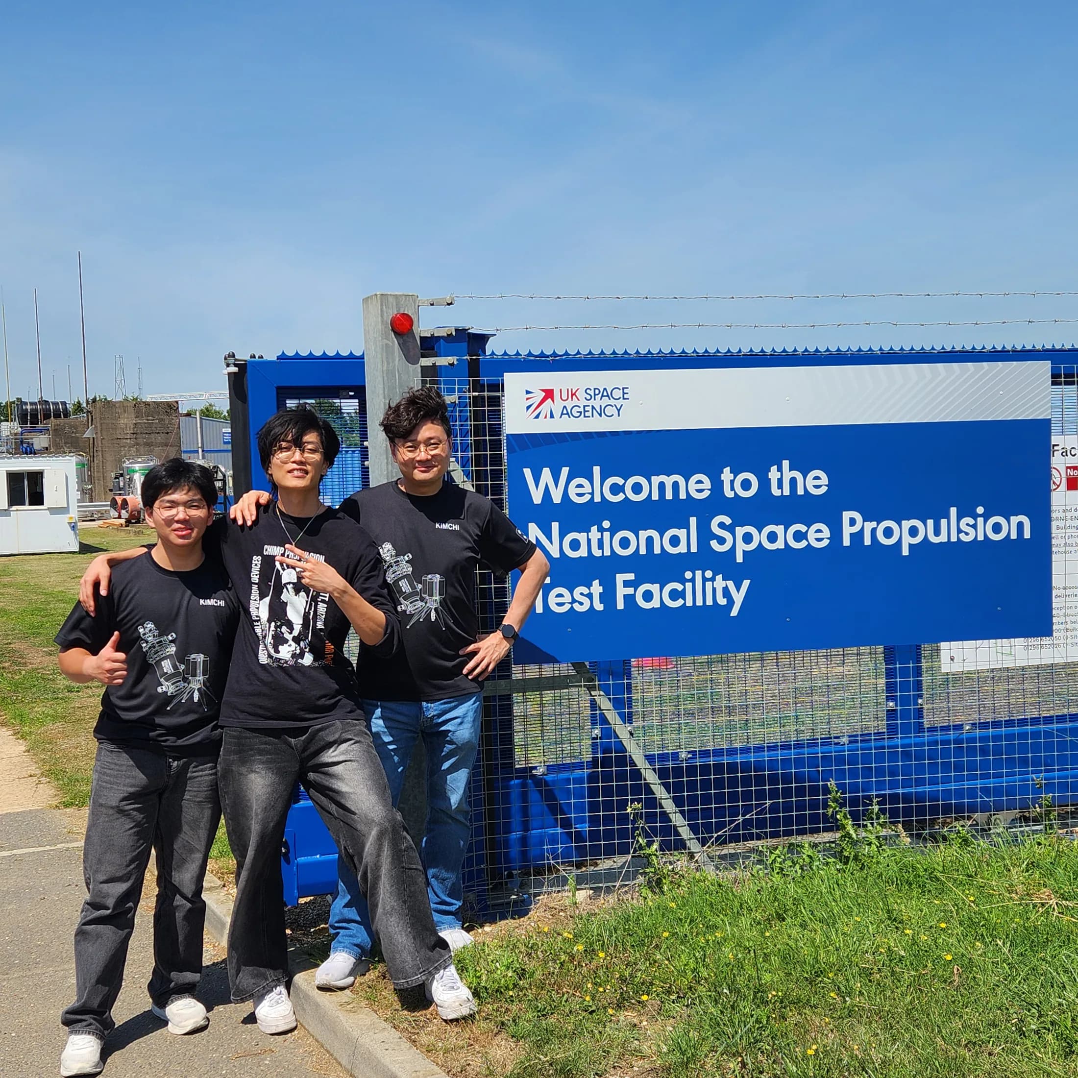Three team members at the National Space Propulsion Test Facility sign.