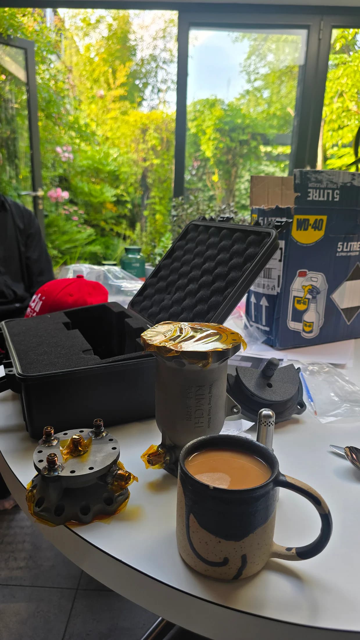 Indoor table with event materials, drinks, a cap, and equipment cases on the evening before testing.