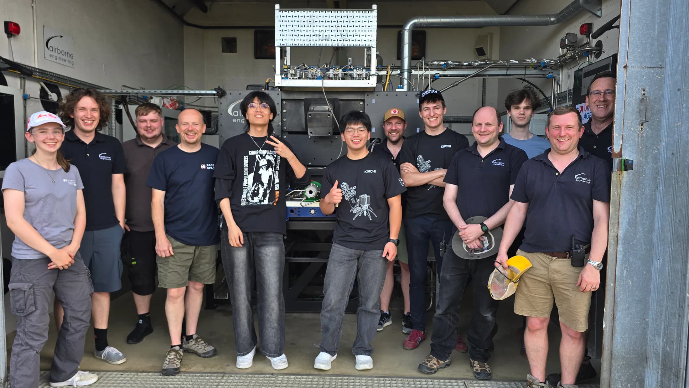 Kimchi team and facility personnel standing together inside the test-bay doorway after the campaign.
