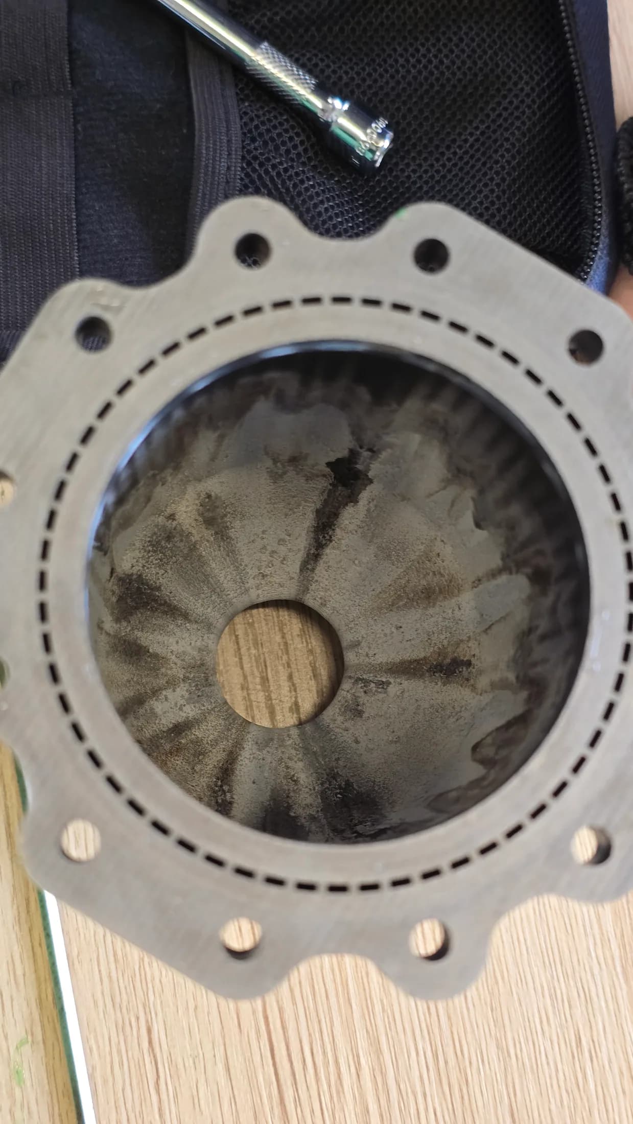 Close-up of a circular engine face with dark radial marks after testing.