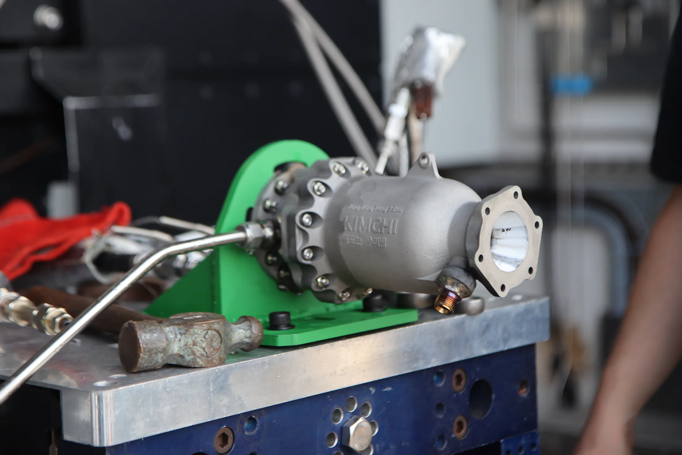 Clean side profile of the engine assembly on its green test-stand bracket with tubing attached.