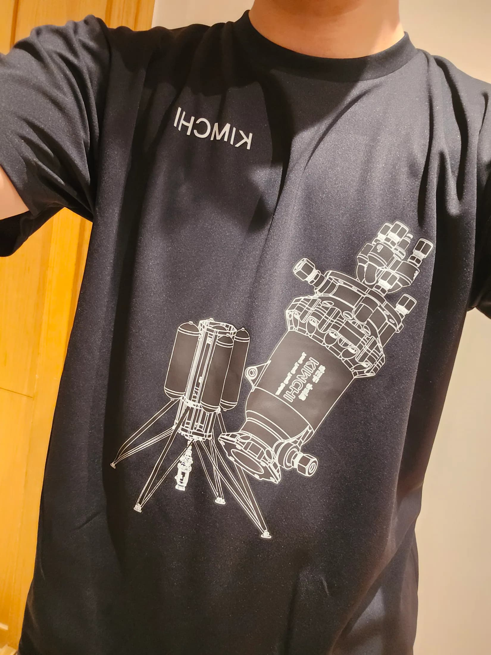 Close-up of a black team shirt printed with a white spacecraft and lander line drawing.