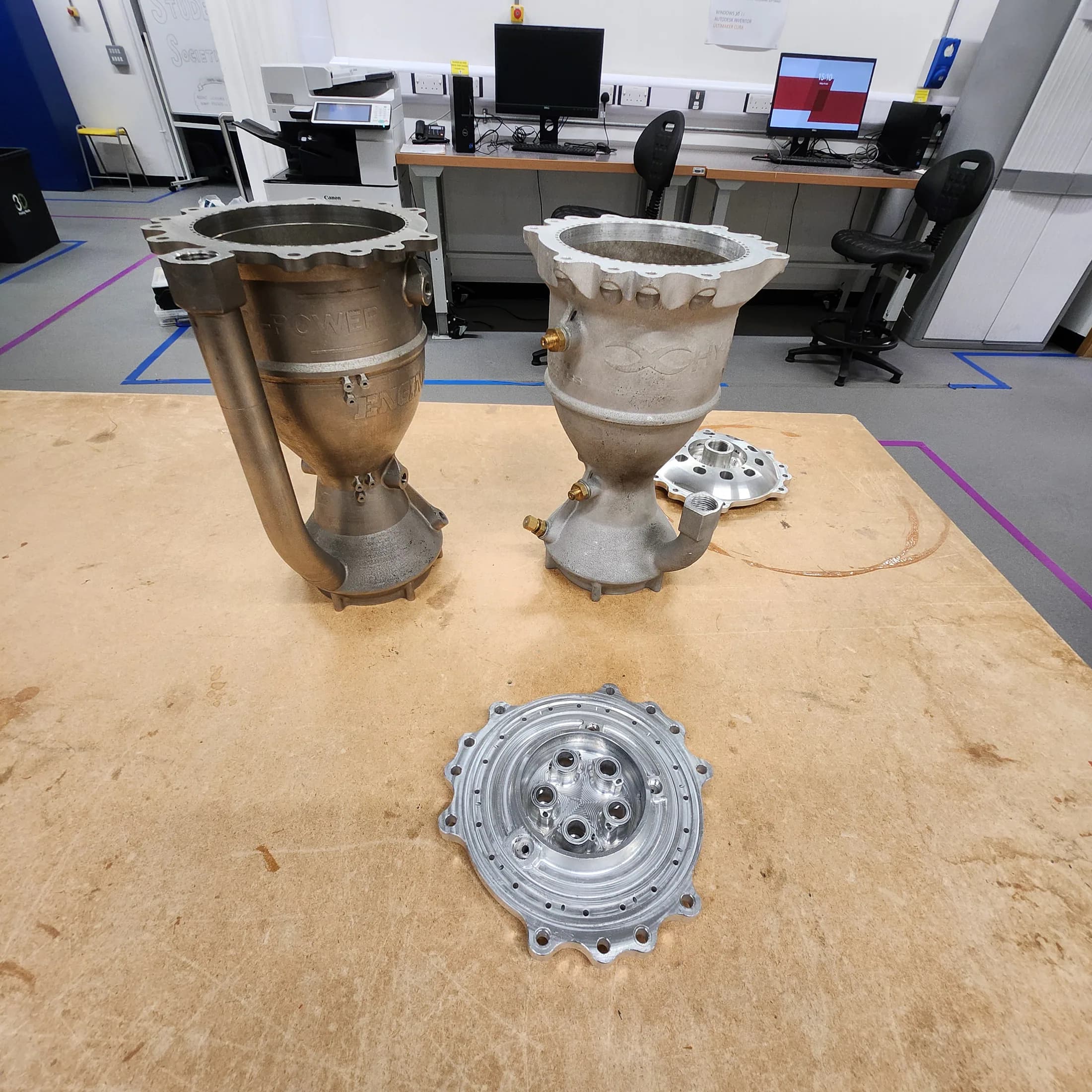 Large metal propulsion components and a circular machined part displayed on a Bristol workshop table.