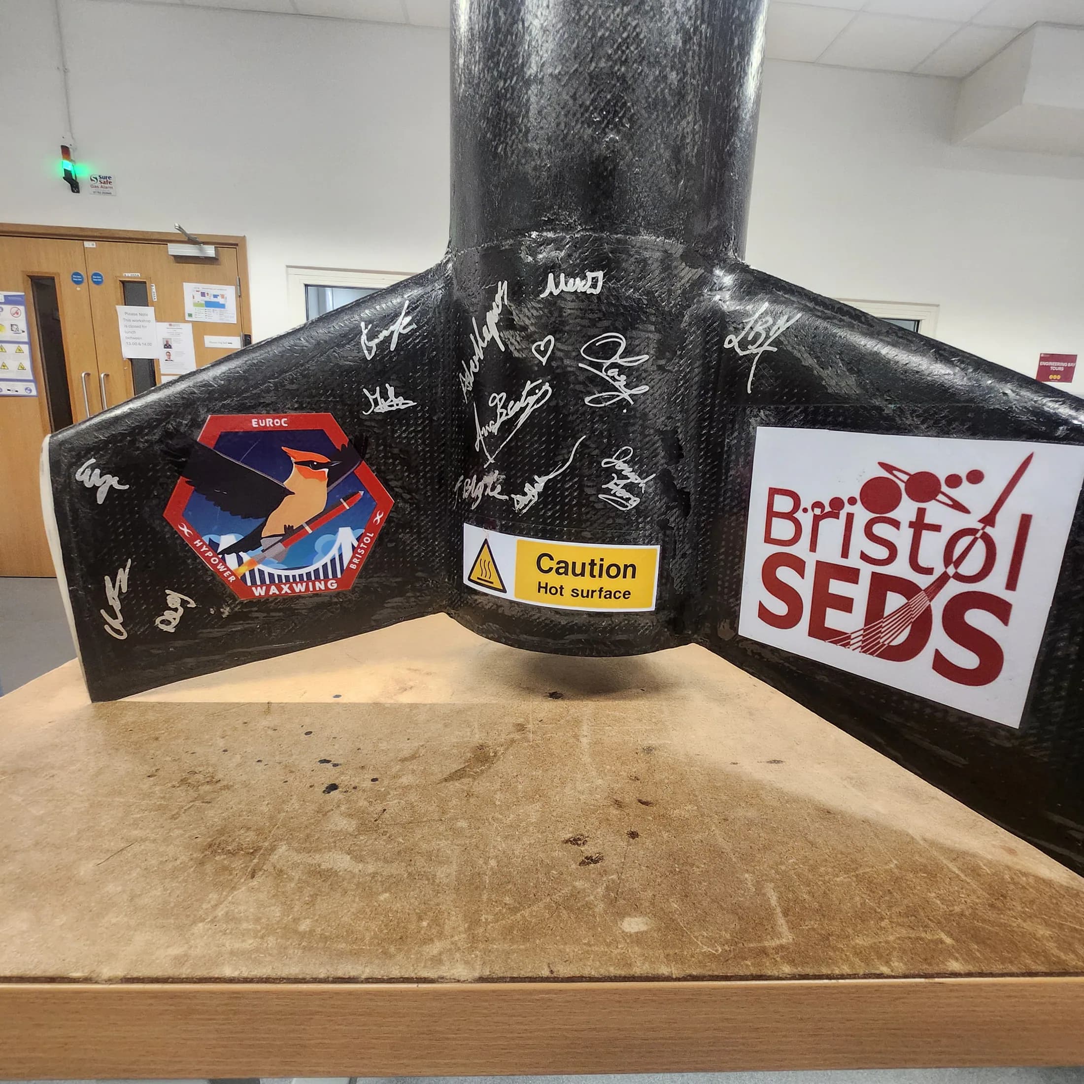 Close-up of a signed black rocket fin section with decals and a Bristol SEDS mark.