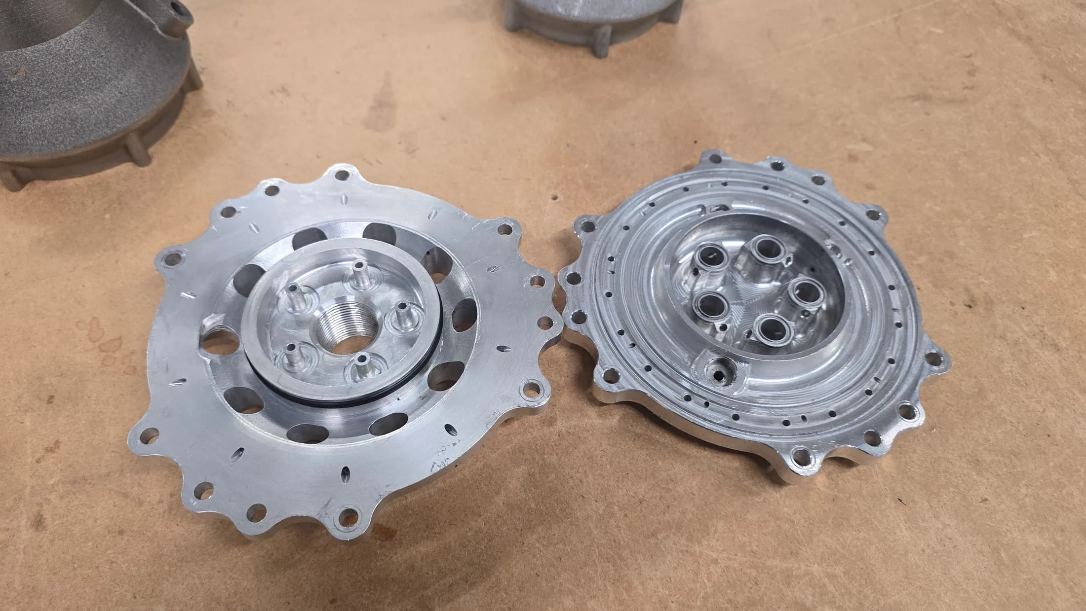 Two circular machined metal components placed on a wooden workbench.