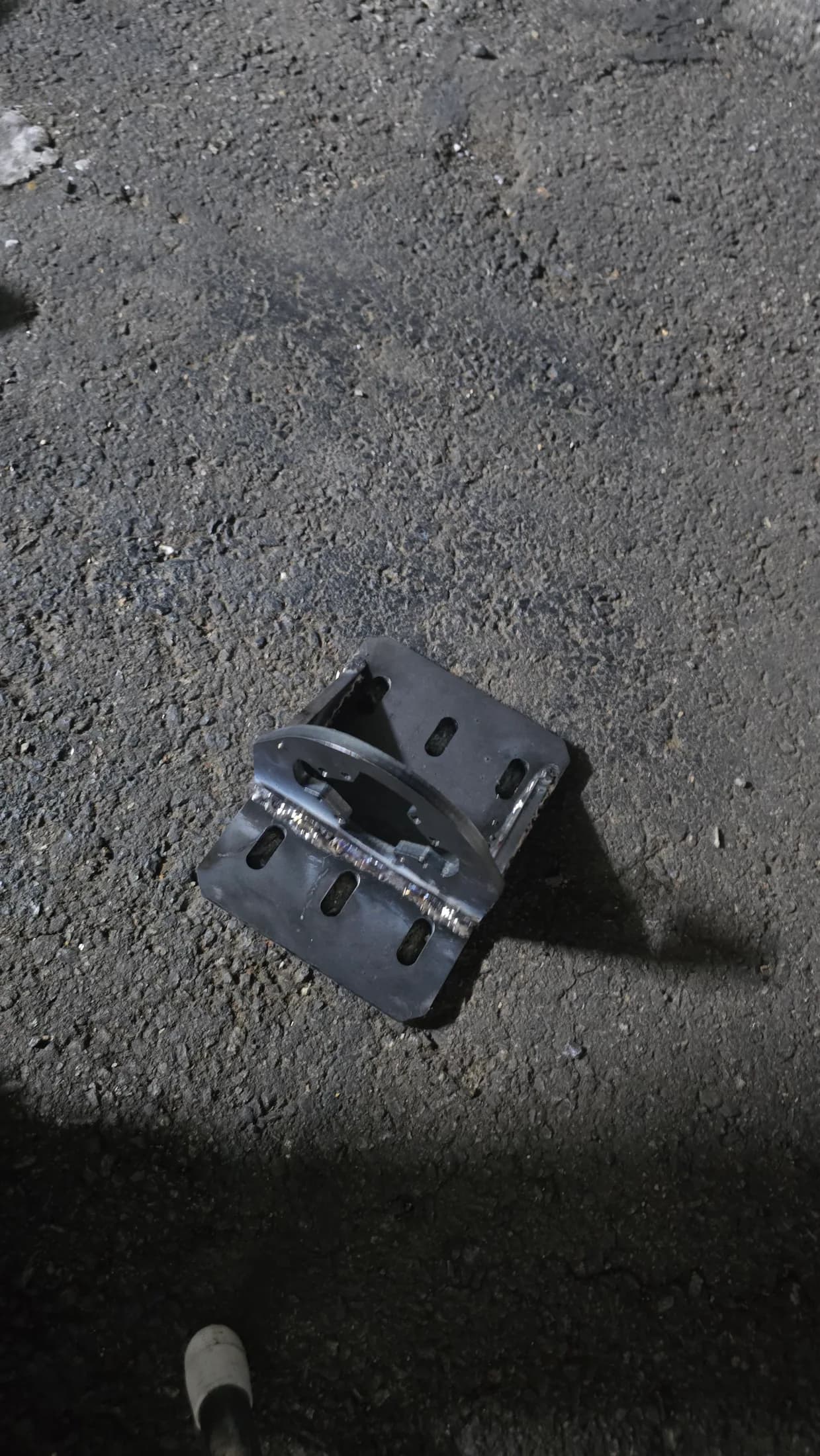 Small metal bracket placed on the ground during a nighttime setup session.