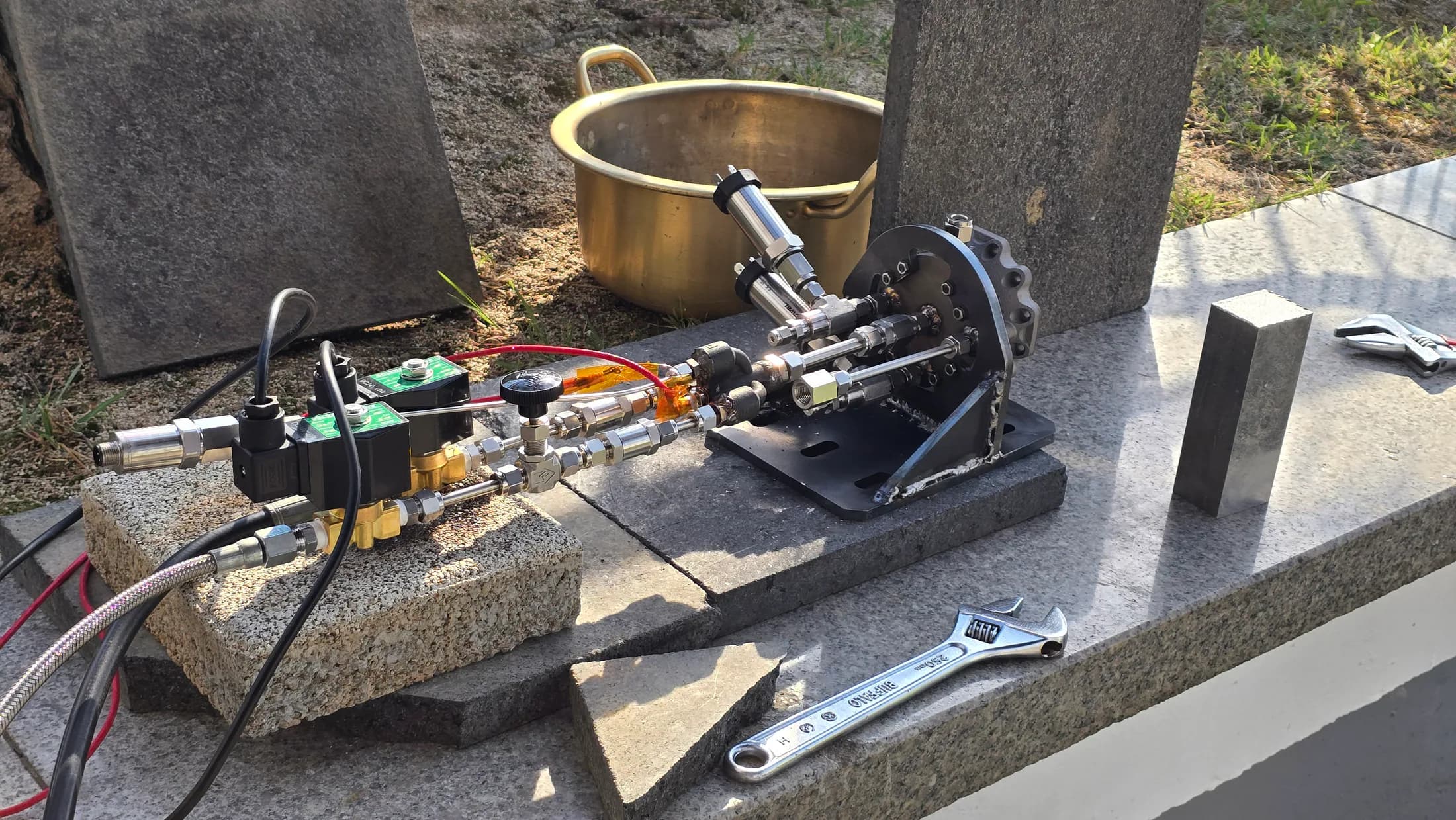 Injector test assembly prepared outdoors with wiring, fittings, and tools nearby.