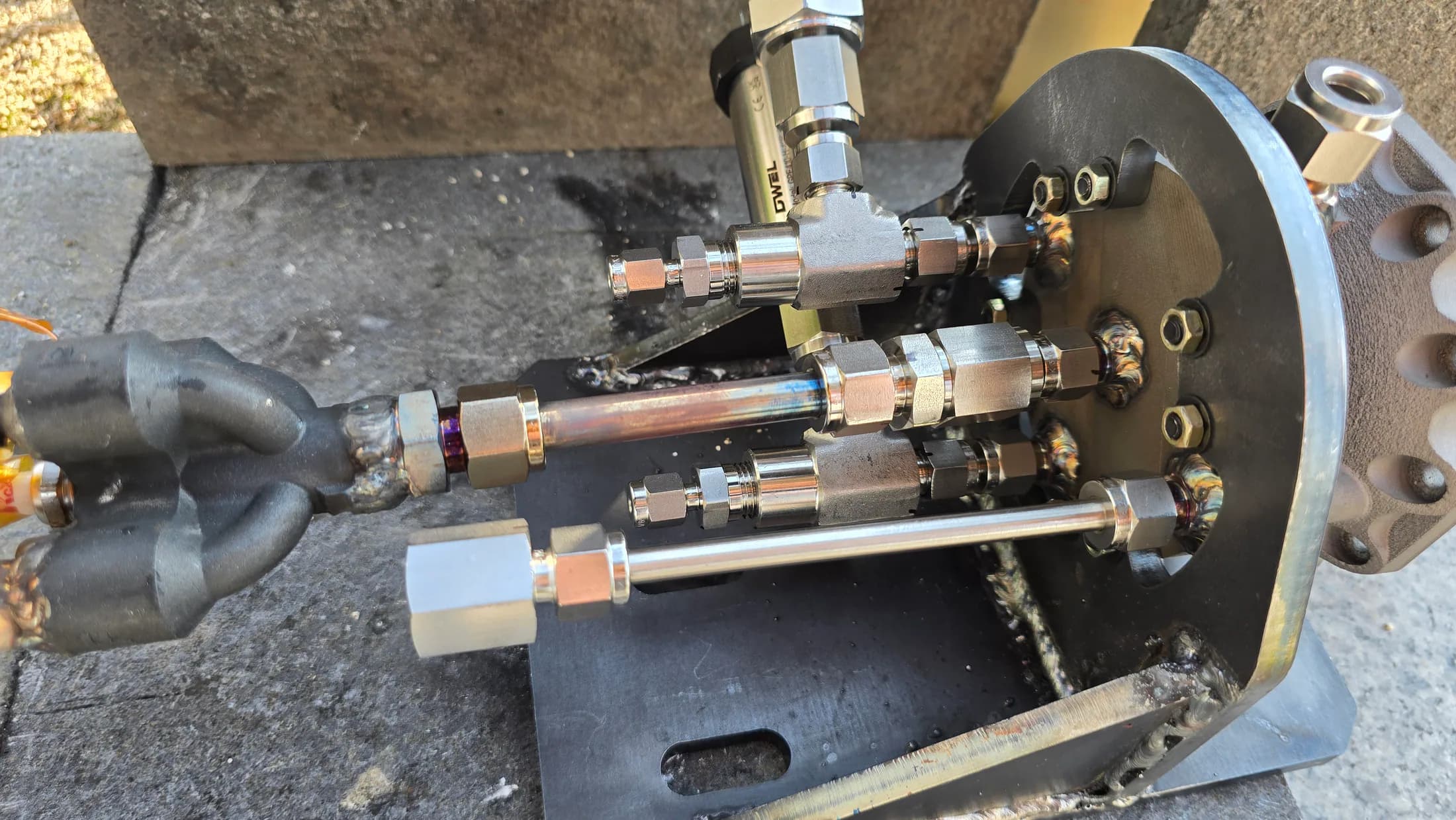 Close-up of injector manifold plumbing with several metal feed lines and fittings.