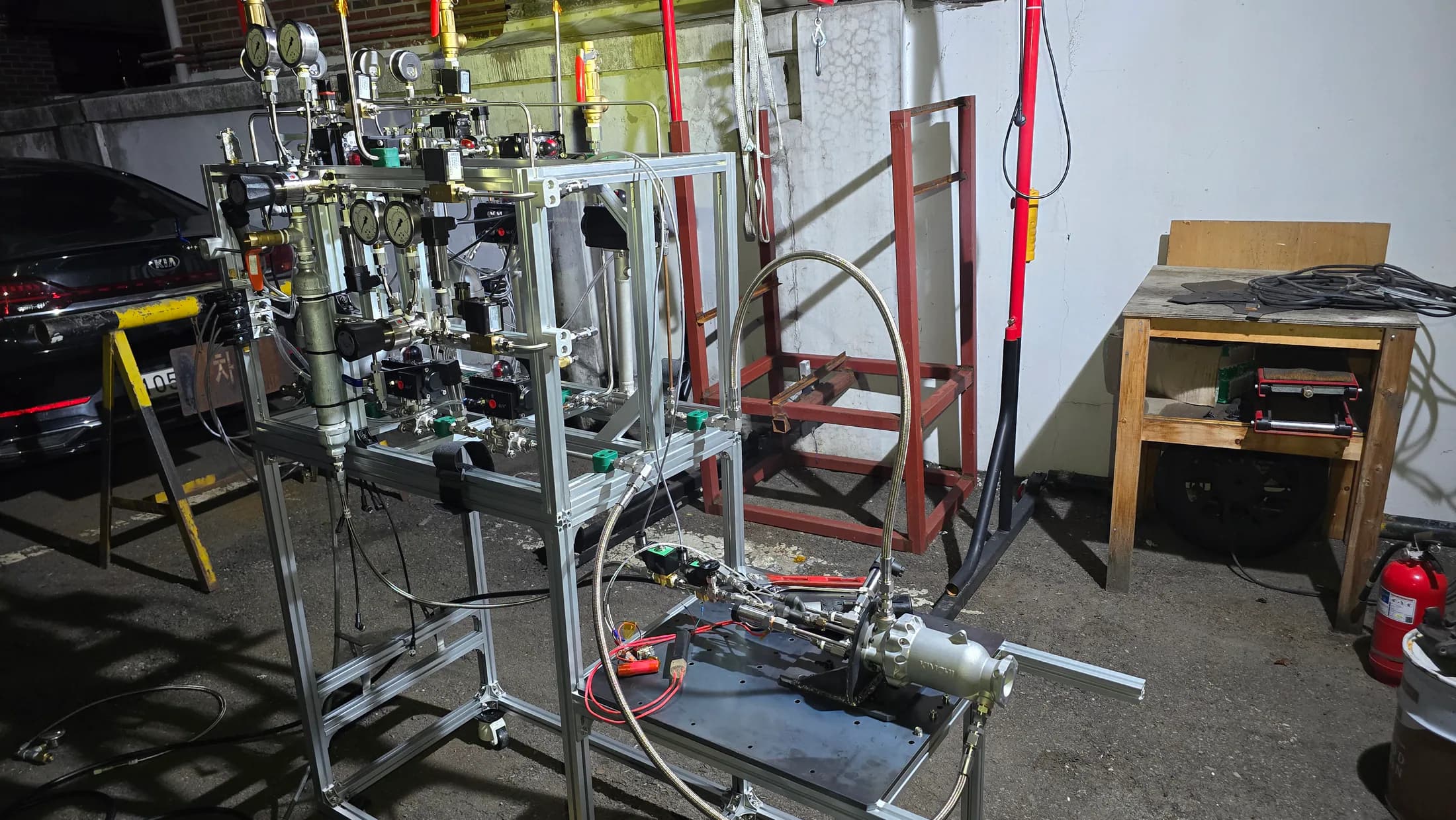 Night view of the full small-engine ground test stand with frame, bottles, tubing, and engine hardware.